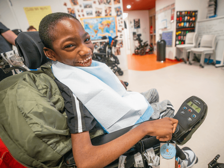iHOPE student in a wheelchair smiling in his classroom.